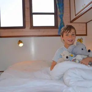 Ein Kind mit mehreren Plüschtieren in einem Bett.