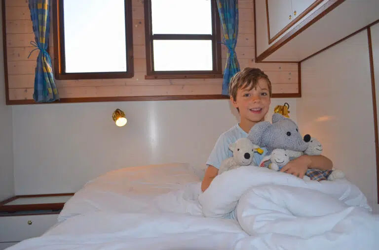 Ein Kind mit mehreren Plüschtieren in einem Bett.