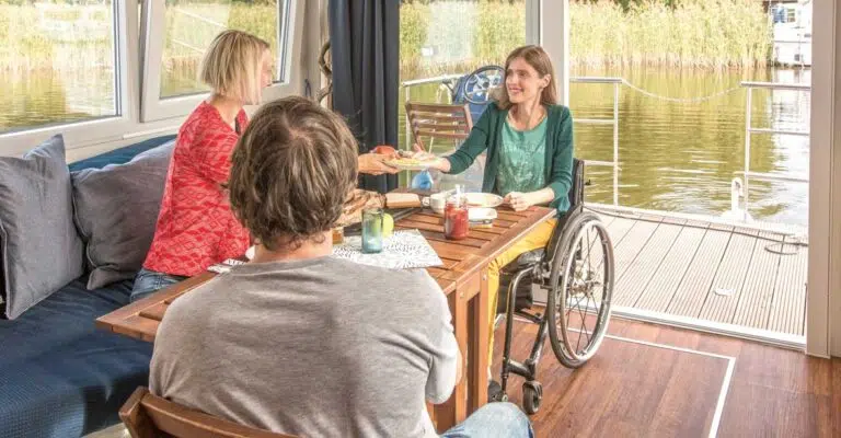 Drei Personen im Salon eines Febomobils, u.A eine Rollstuhlfahrerin