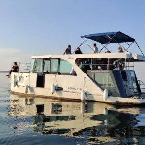 das Boot Aquino auf einem stillen See, an Deck sind 6 Personen