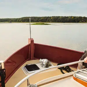 ein junger Mann steht vorne auf dem Boot Aquanaut und sieht auf den See
