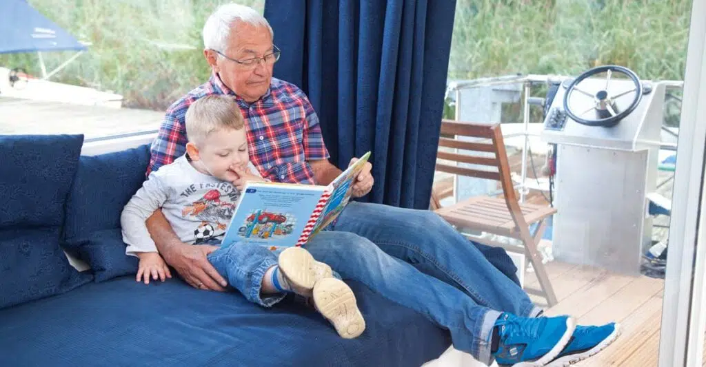 Ein Opa liest ein Buch mit seinem Enkel im Salon eines Febomobils