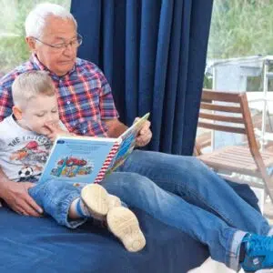 Ein Opa liest ein Buch mit seinem Enkel im Salon eines Febomobils