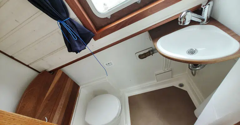 Badezimmer der Kuinder und Waschbecken mit beweglichem Duschkopf. Die Toilette kann abgedeckt werden mit einer Platte in Holzoptik.