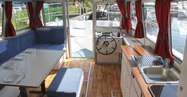 Salon der Pirate 1200 mit blau gepolsterter Sitzecke und einer Küchenzeile.