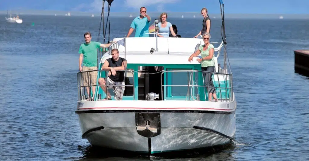 Bugansicht der Vetus 1500, ein weiß-grünes Boot mit roten und Schwarzen Akzenten. Auf dem Boot befindet sich eine Gruppe. Drei Personen sind im Vordergrund auf dem Bug, Drei Personen sind im Hintergrund auf dem Heck.
