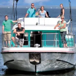 Bugansicht der Vetus 1500, ein weiß-grünes Boot mit roten und Schwarzen Akzenten. Auf dem Boot befindet sich eine Gruppe. Drei Personen sind im Vordergrund auf dem Bug, Drei Personen sind im Hintergrund auf dem Heck.