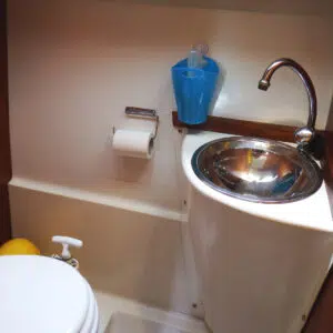 Badezimmer mit manueller Toilette und Edelstahlwaschbecken