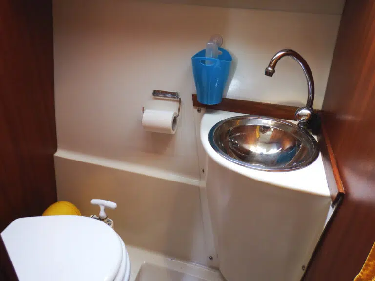 Badezimmer mit manueller Toilette und Edelstahlwaschbecken