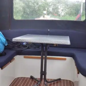 Eine blau gepolsterte Sitzecke im Cockpit der Almeria 850 mit einem kleinen Tisch in Marmoroptik in der Mitte.