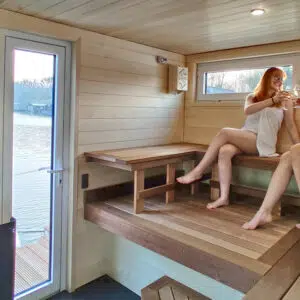 Zwei junge Frauen im Saunabereich des Saunahausbootes stoßen auf ein Glass Weißwein an.