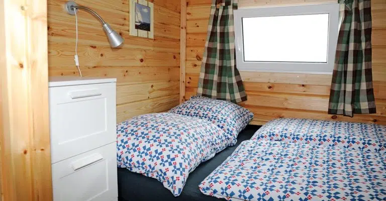 Die Kabine im Heck der Sundeck 400 mit einem Doppelbett. Das die Decken und Kissen sind bezogen mit weißen Bezügen mit Blau-rotem Muster.